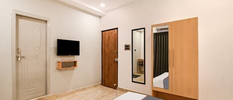 A hotel room with a bed, a television, a wardrobe, and a mirror.