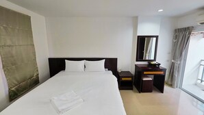 A hotel room with a large bed, a desk, a mirror, and a window with curtains. - Ahmara A Recall Value Hotel Patong, Phuket (Patong)