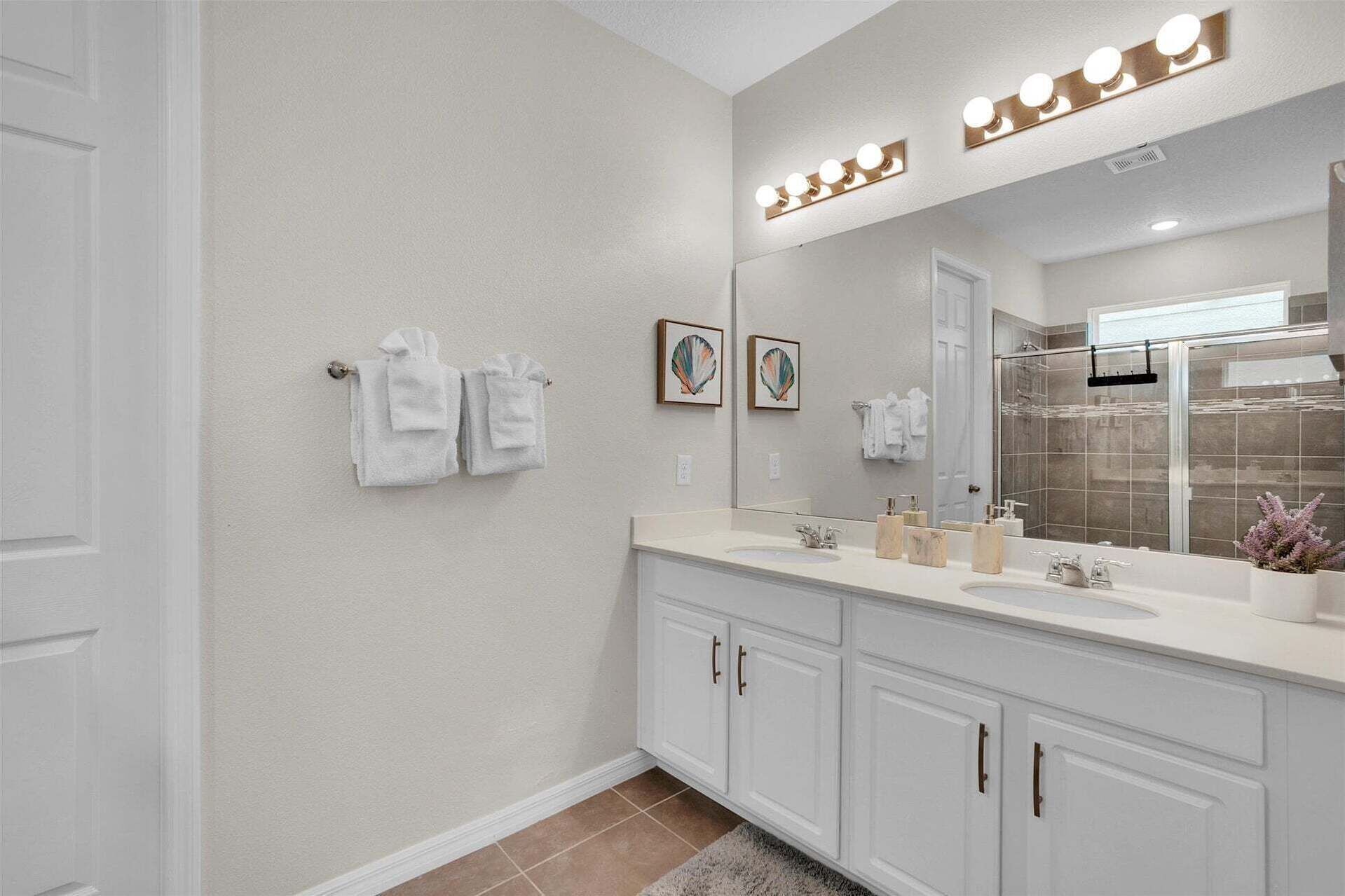 A bathroom with a large mirror, vanity, and towel rack.