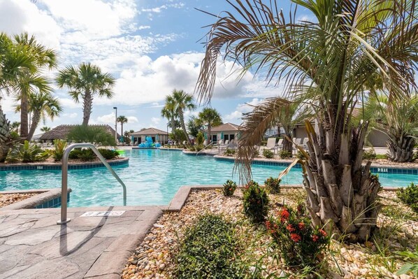 A pool area with clear blue water, surrounded by palm trees and a stone deck. - 1426 Wexford WAY Davenport, 8bed (Davenport)