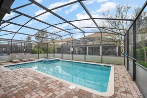An indoor swimming pool with a brick floor and a metal roof structure. - 1426 Wexford WAY Davenport, 8bed (Davenport)