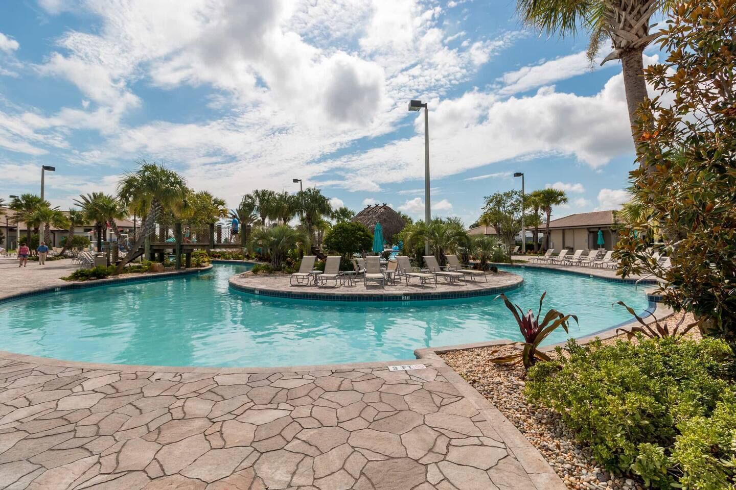 A swimming pool with lounge chairs and palm trees.