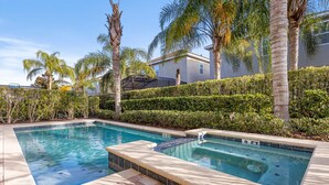 A swimming pool with a tiled deck, surrounded by palm trees and a hedge. - 520-8-ld-large Movie&game Room (Kissimmee)