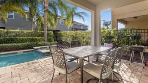 An outdoor patio with a pool, a table with chairs, and a barbecue grill. - 520-8-ld-large Movie&game Room (Kissimmee)
