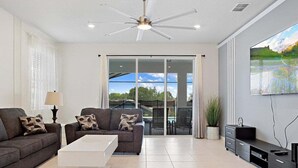 A modern living room with a sofa, coffee table, TV, and a ceiling fan. - 3835la · Brand New 7BR in Windsor Island (Davenport)