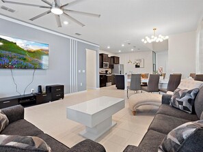 Ein modernes Wohnzimmer mit Flachbildfernseher, Deckenventilator und Essbereich mit Tisch und Stühlen.