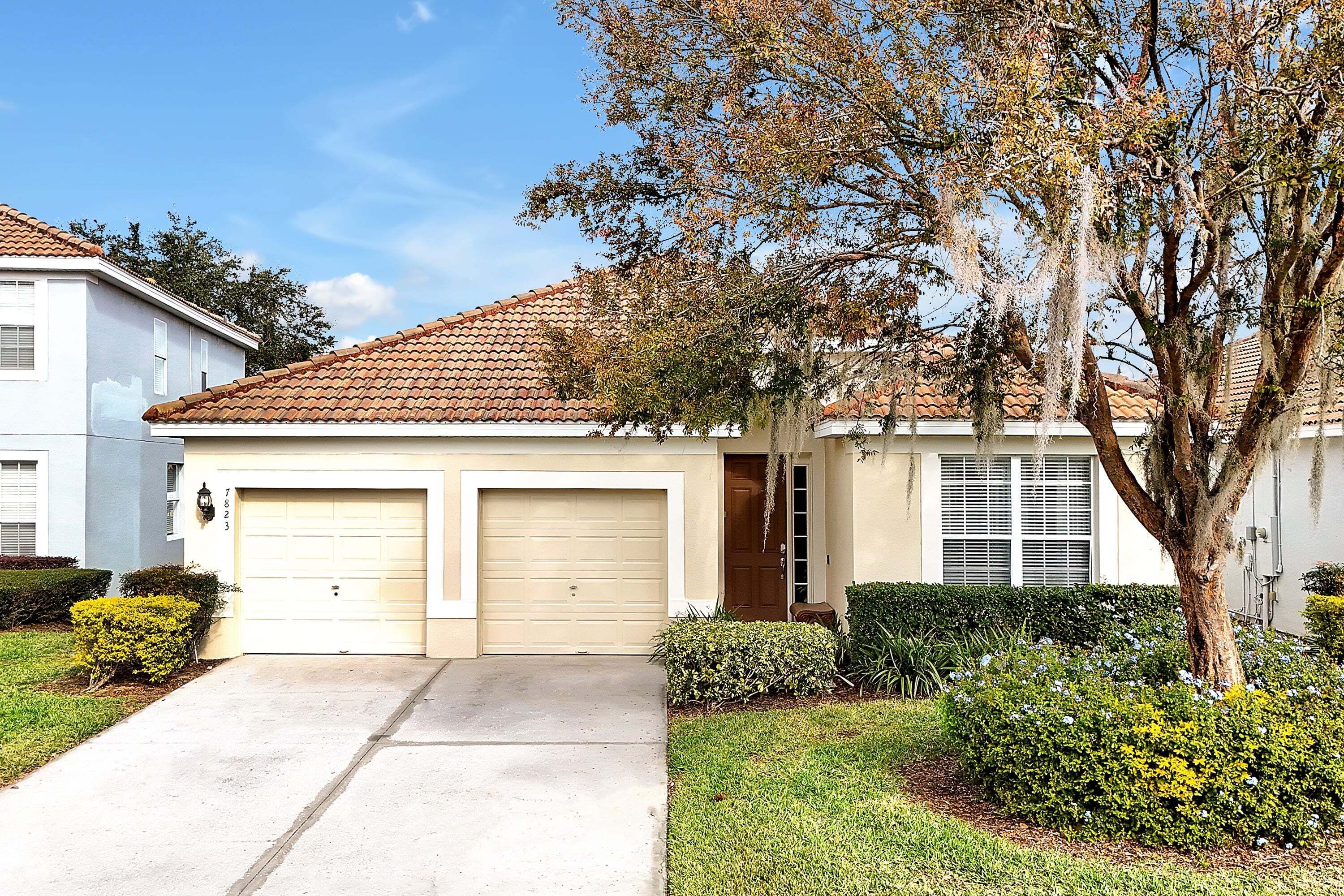 A residential house with a garage, a driveway, and well-maintained landscaping.