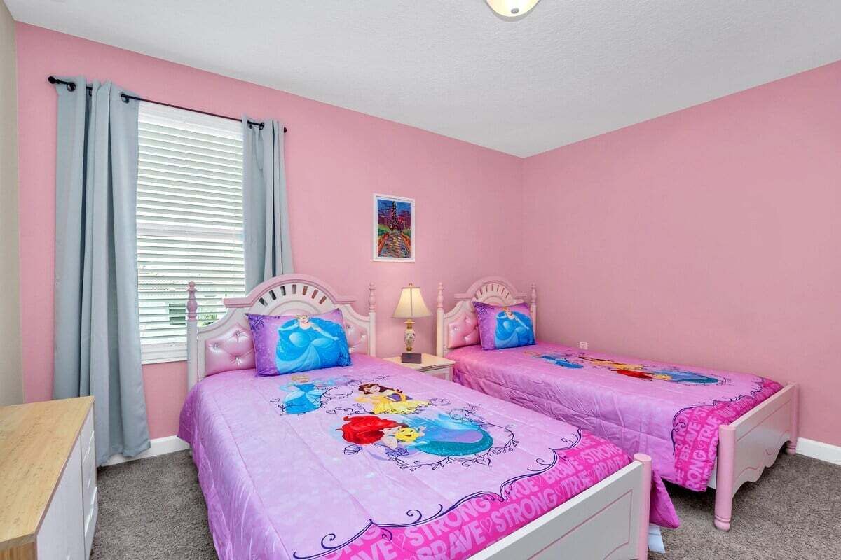 Ett sovrum med två sängar, och varje säng har ett rosa sängöverkast med Disneyprinsessor på.