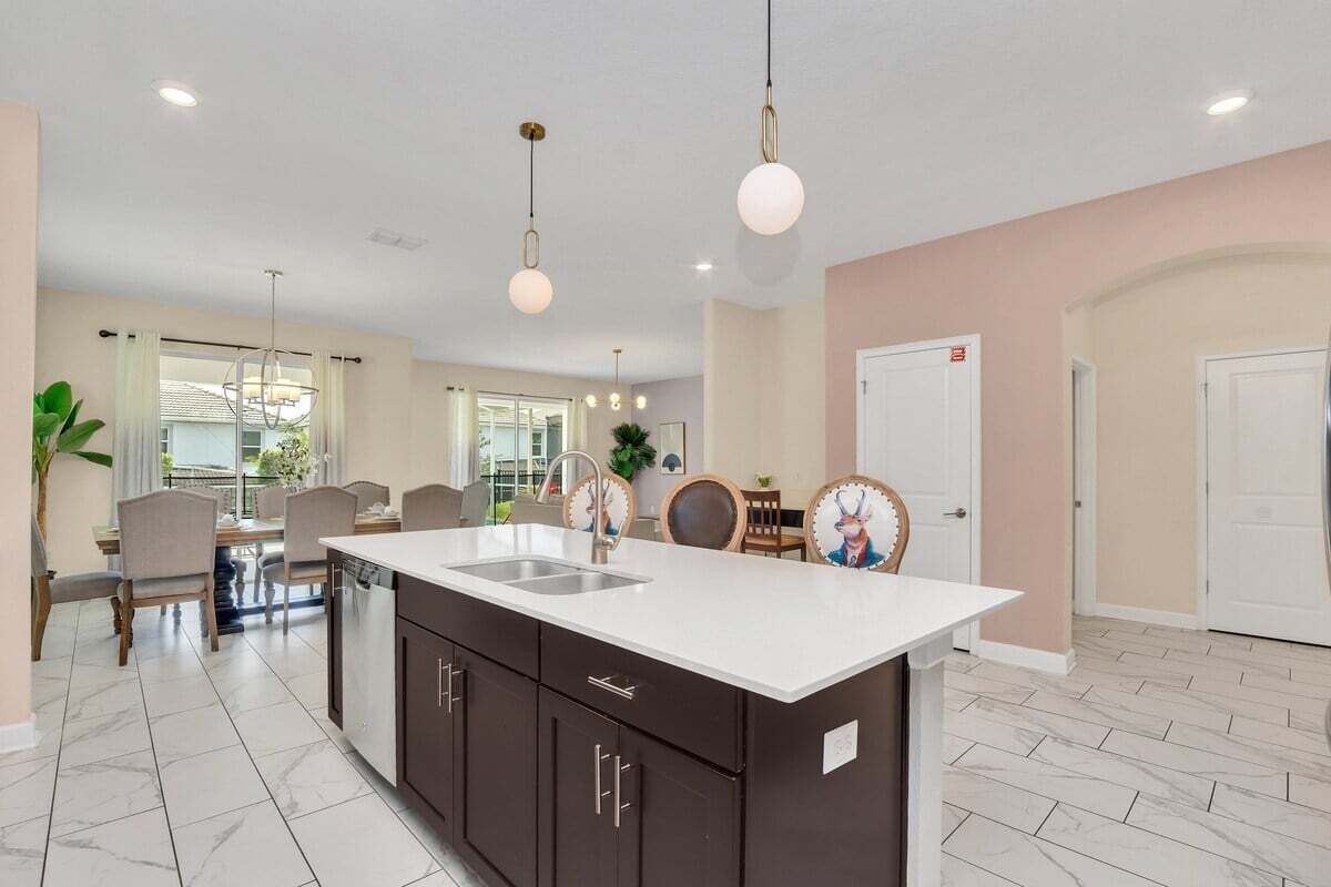 A modern kitchen with a central island, dark cabinetry, and pendant lighting.