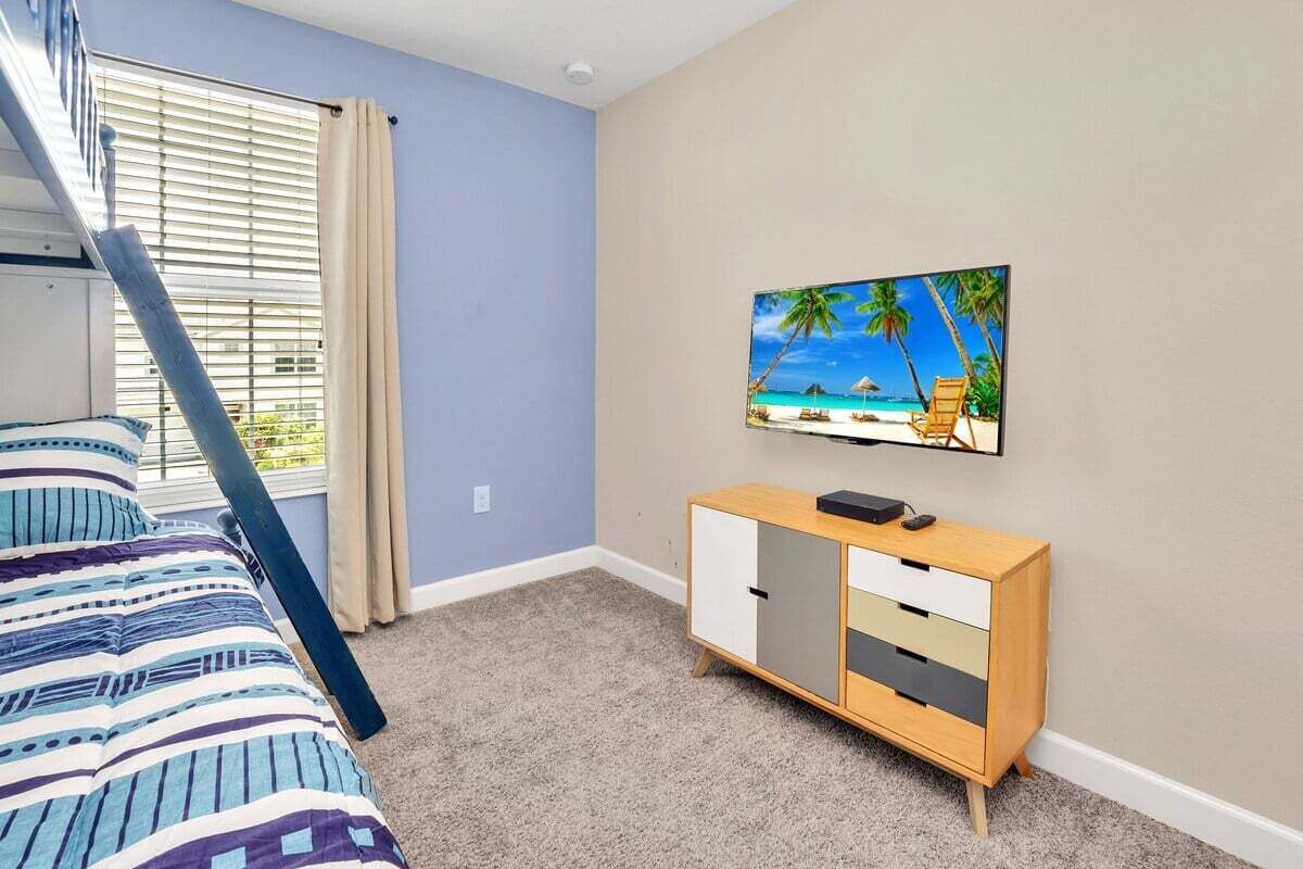 A bedroom with a bunk bed, a wooden cabinet, and a painting of a beach scene on the wall.