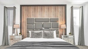 A modern bedroom with a large bed, a wooden headboard, and two bedside tables with lamps. - 8939ad · Amazing Solara 7br/ Pool /spa /free Waterpark (Kissimmee)