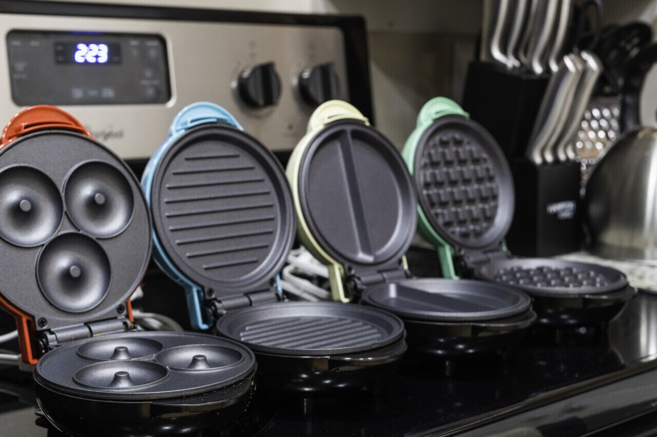 A kitchen with a stove and various waffle irons.