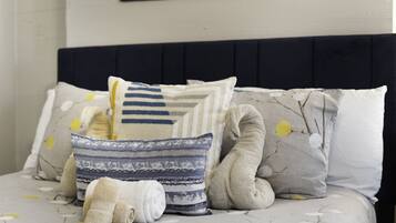A neatly made bed with a dark headboard, multiple pillows, and a decorative pillow with a branch pattern.