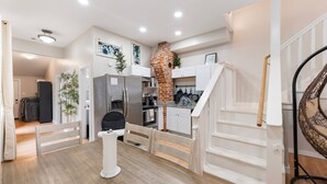 A compact kitchen with white cabinets, a brick oven, and a dining area with a white table and chairs. - 4 Queen Beds High Speed Wifi Private Parking (Fort Worth)