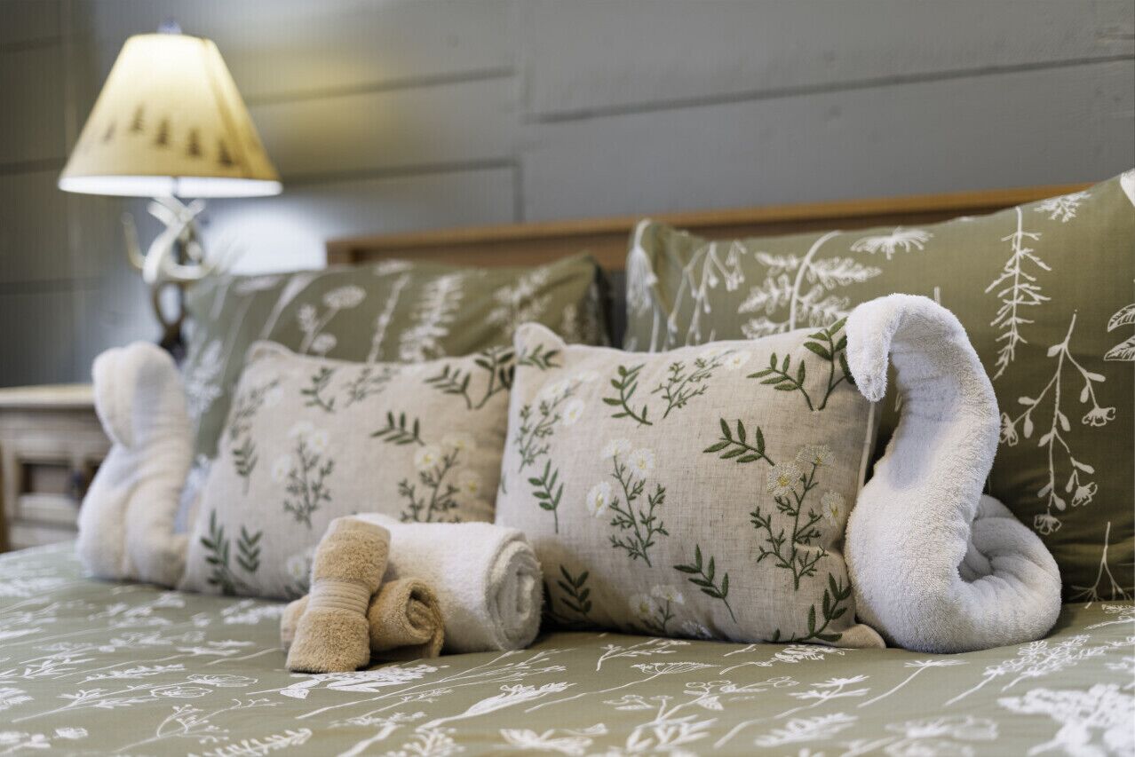 Un lit avec des oreillers à motifs floraux et une serviette enroulée.