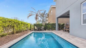 A rectangular swimming pool with a tiled deck, surrounded by a landscaped garden with various plants and a palm tree. - 541-7-ld-dream Home - Private Pool&spa (Kissimmee)