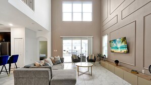 A spacious living room with a sectional sofa, a round coffee table, and a large window providing natural light. - 1085 Leader ST, Davenport,5 BED (Davenport)