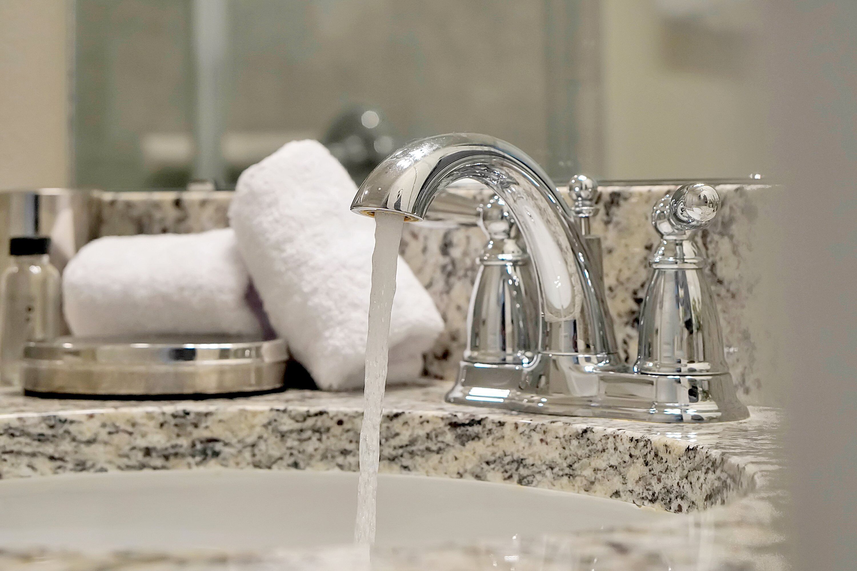 Un lavabo de salle de bain doté d’un robinet moderne et d’un plan de toilette en marbre.