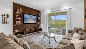A modern living room with a large flat-screen TV, a glass coffee table, and a sofa. - 371-8-pc-fabulous Home With Private Pool and spa (Kissimmee)