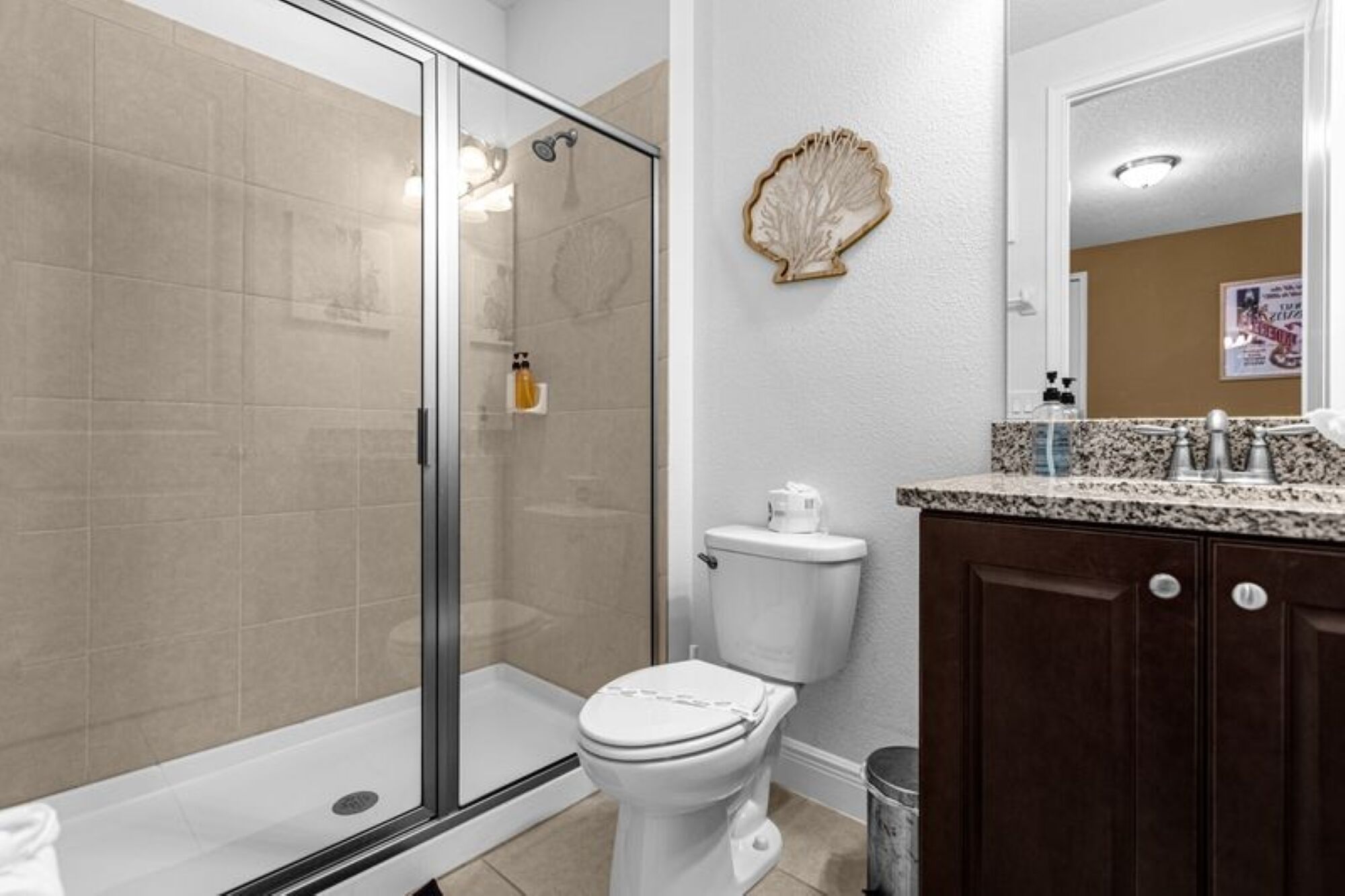 A bathroom with a glass shower enclosure, a toilet, and a vanity with a mirror.