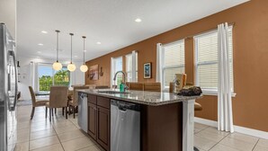 A spacious kitchen with a large island, modern pendant lighting, and a view of the outdoors. - 371-8-pc-fabulous Home With Private Pool and spa (Kissimmee)