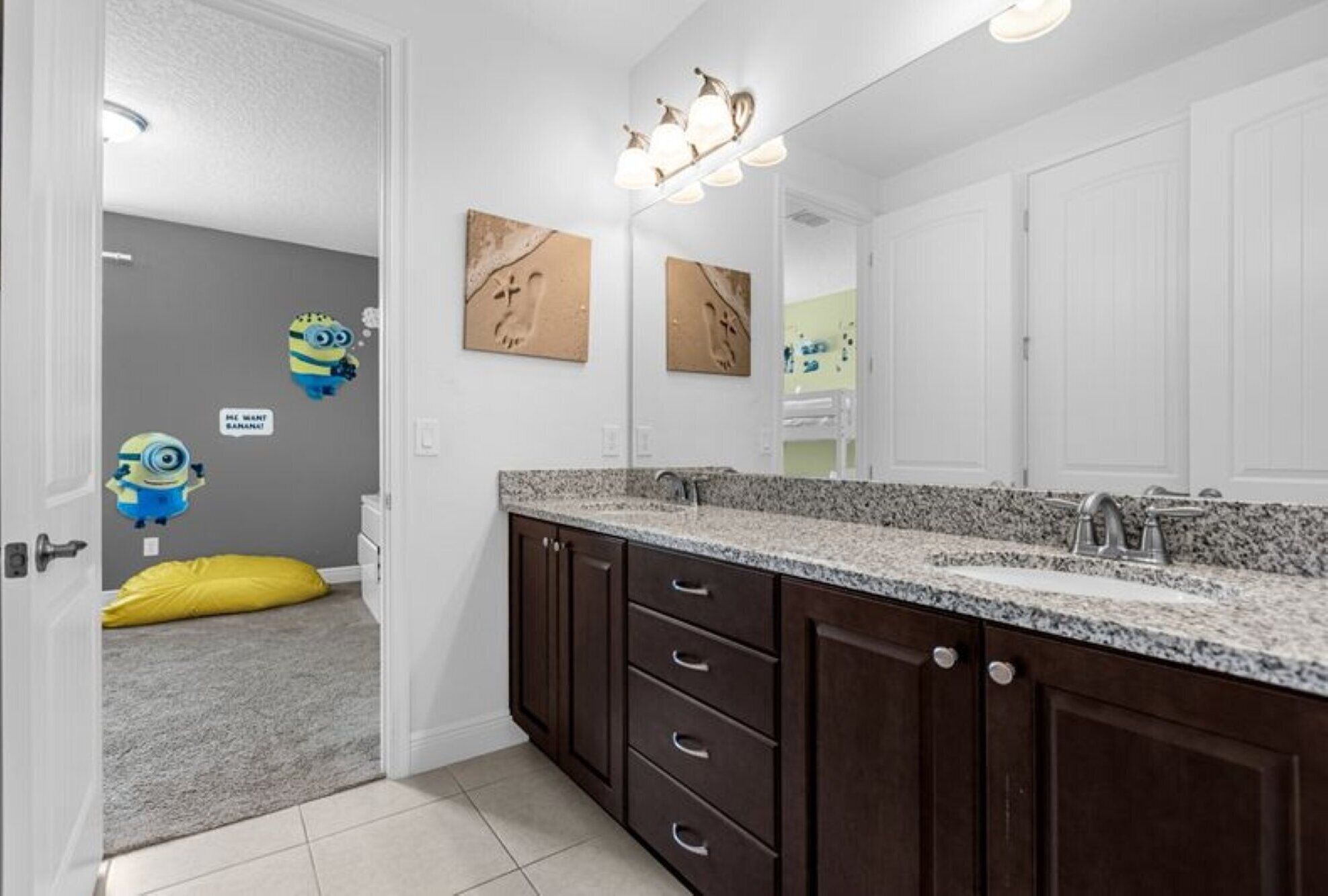 A modern bathroom with a granite countertop, dark wooden cabinets, and a large mirror.