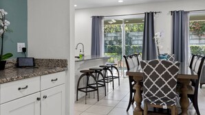 Eine moderne Küche mit einer Granit Arbeitsplatte, weißen Schränken und einer kleinen Topforchidee.
