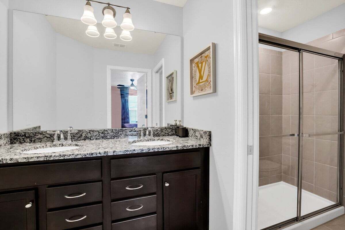 Une salle de bain avec un meuble-lavabo à deux vasques, un grand miroir et une douche à l’italienne.
