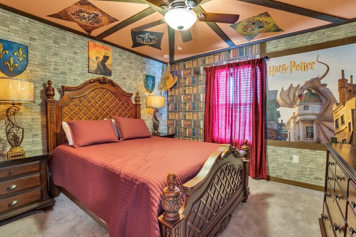 A bedroom with a large bed, a ceiling fan, and a bookshelf.