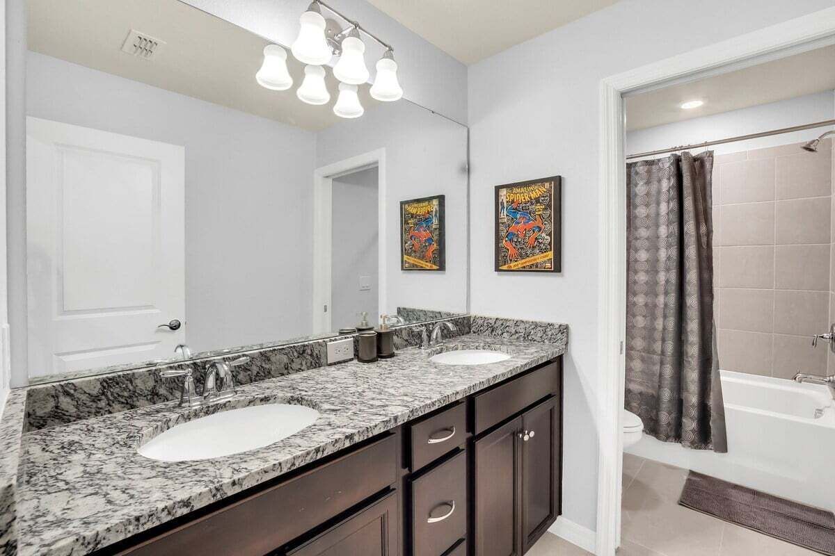 Un baño con dos lavamanos, un espejo grande y una ducha.