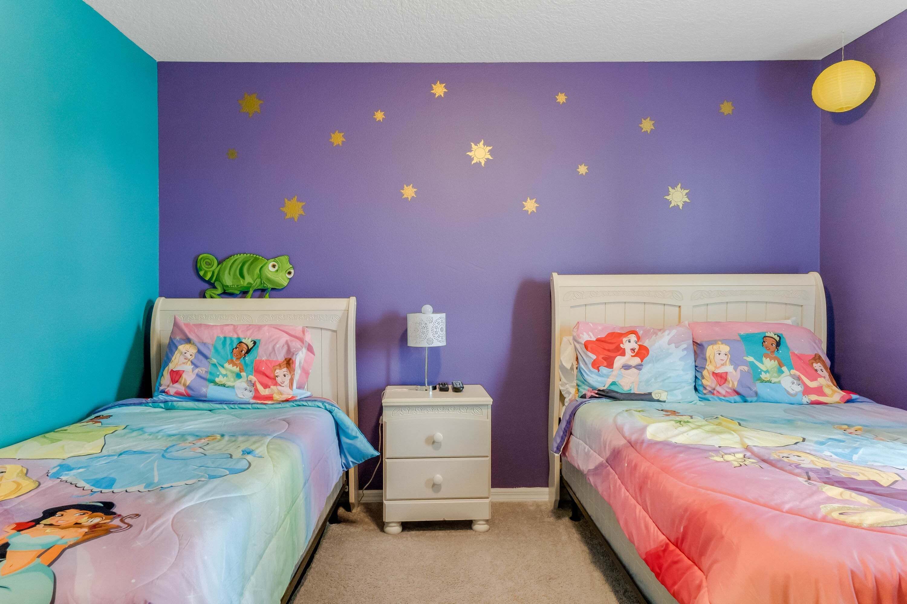 Un dormitorio con dos camas, estrellas decorativas en la pared y una mesita de noche con una lámpara.