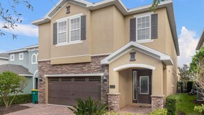 A two-story house with a stone facade, a garage, and a front door. - 431-7-np-gateaway With Screened Pool (Kissimmee)