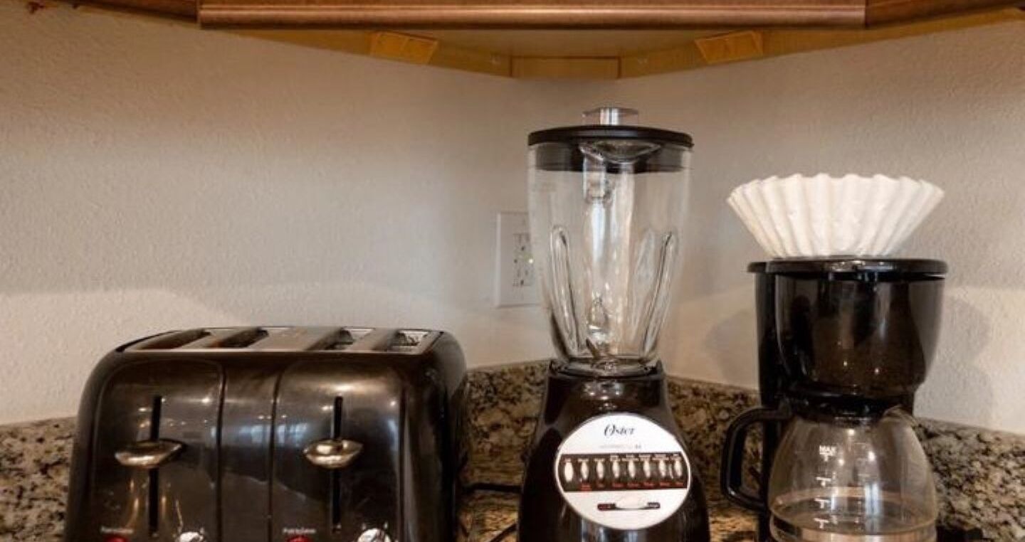 A kitchen with a blender and a coffee maker on a granite countertop.