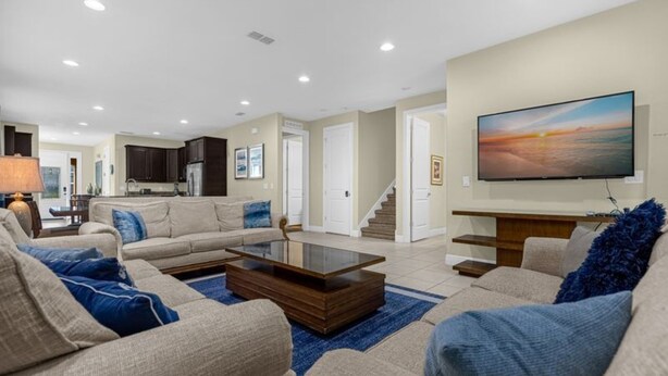 A spacious living room with a large flat-screen TV, a sofa set, a coffee table, and a kitchen in the background. - 431-7-np-gateaway With Screened Pool (Kissimmee)