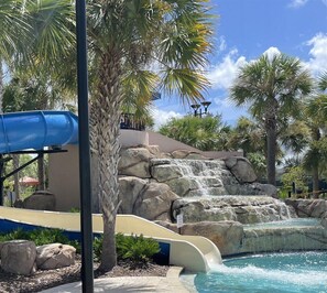 A water park with a blue slide, a rock waterfall, and a pool. - 4159-5-ot-contemporary Resort Villa (Davenport)