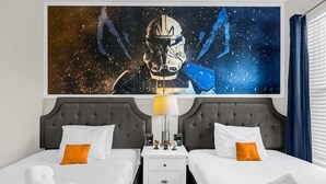 Een hotelkamer met twee bedden, een nachtkastje, een lamp en een groot kunstwerk met een ruimte thema aan de muur.