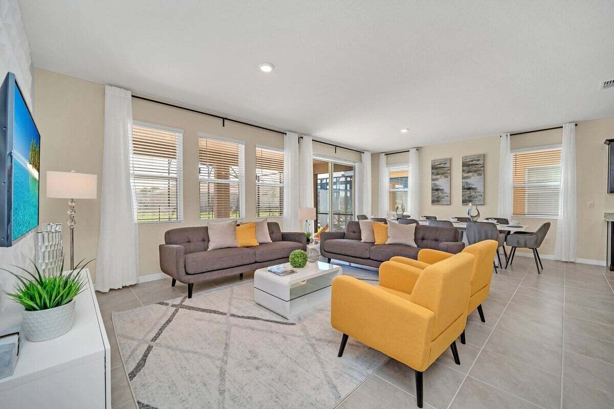 A spacious living room with a sofa set, a coffee table, and a dining area with chairs.