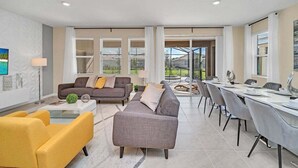 Een moderne woonkamer met een bank, stoelen en een eethoek met een tafel en stoelen.