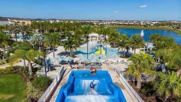 Un parc aquatique doté d’une grande piscine, de palmiers et offrant une vue sur les environs.