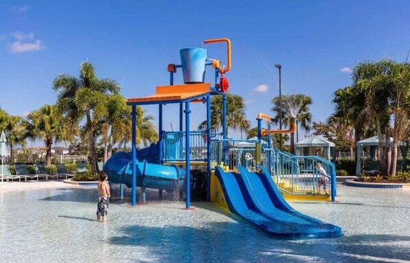 A water park with a blue and yellow play structure, palm trees, and a clear sky. - 9031srl Luxury 9beds Villas With Pool Spa In Solara (Kissimmee)