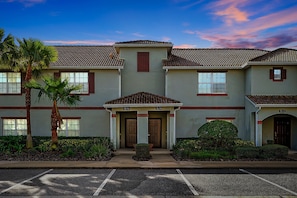 A building with a symmetrical facade, two doors at the center, and a parking lot in front. - 1576 Moon,champions Gate,4bed (Davenport)