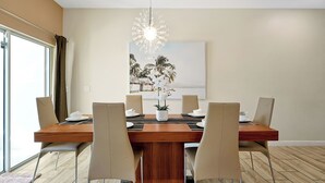 A dining area with a wooden table, six chairs, a chandelier, and a painting on the wall. - 1576 Moon,champions Gate,4bed (Davenport)