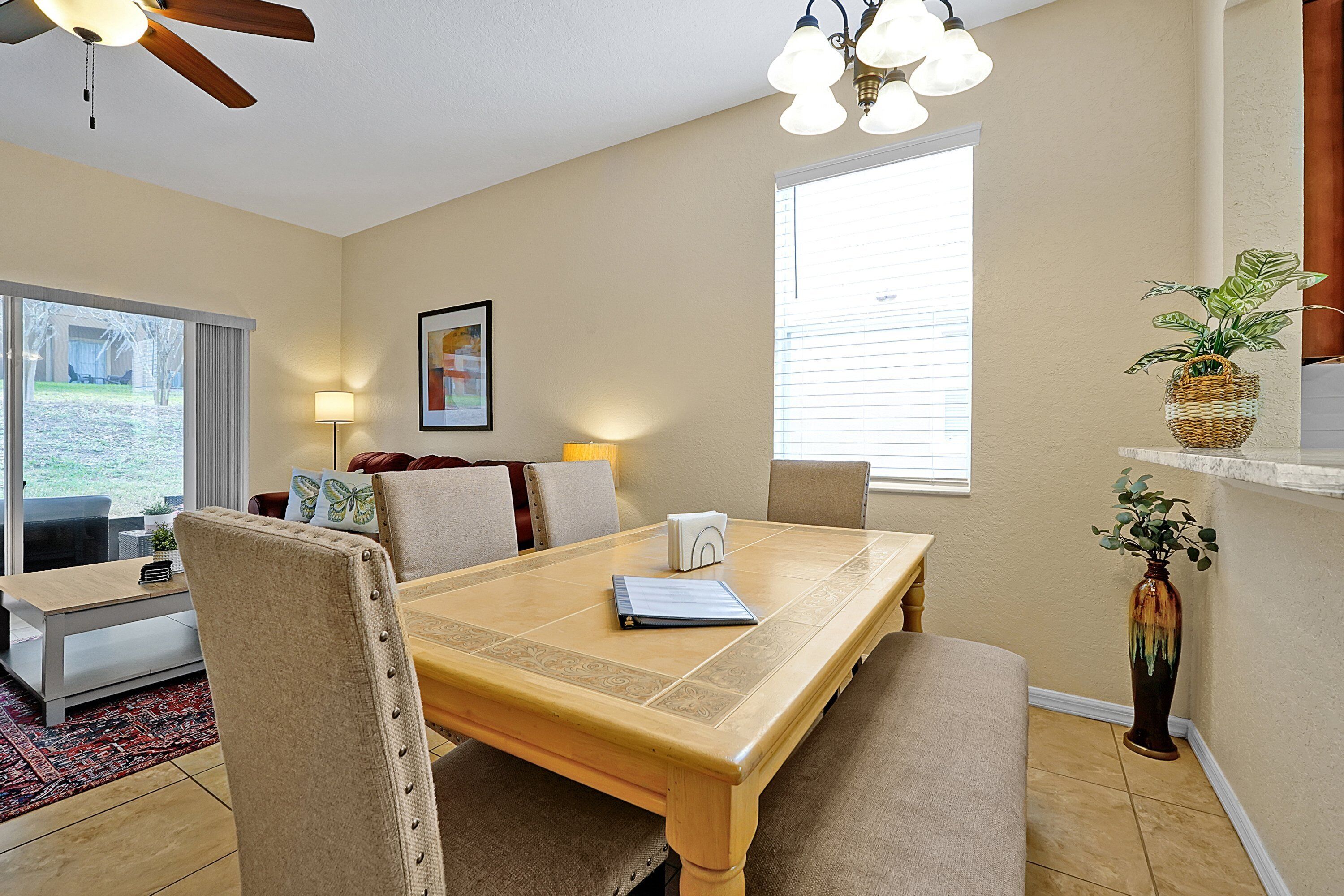 A dining area with a wooden table, beige chairs, and a vase with a plant.