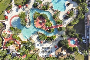 Vista aérea de um resort com várias piscinas, espreguiçadeiras e palmeiras.