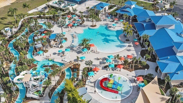 An aerial view of a resort with a large central pool, multiple water slides, and a variety of outdoor seating areas. - 1891sd · Brand New 7br/pool/spa/ Disney Fireworks View (Davenport)