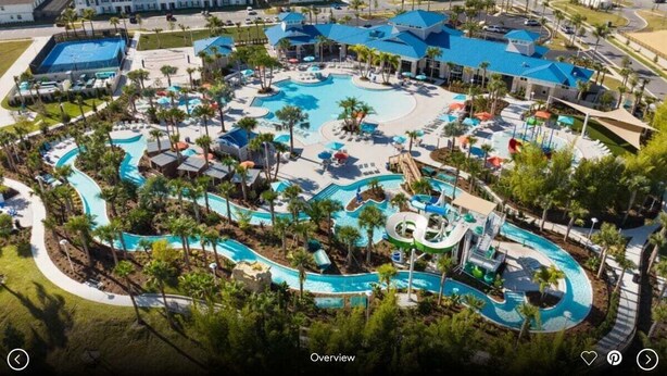 Ein Luftbild zeigt einen Resort mit großem Poolbereich, mehreren Wasserrutschen und verschiedenen Villen sowie Gästezimmern.