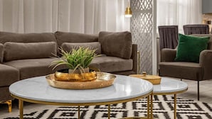 Ein Wohnzimmer mit einer Couch, zwei Sesseln, einem Couchtisch und einer Zimmerpflanze.