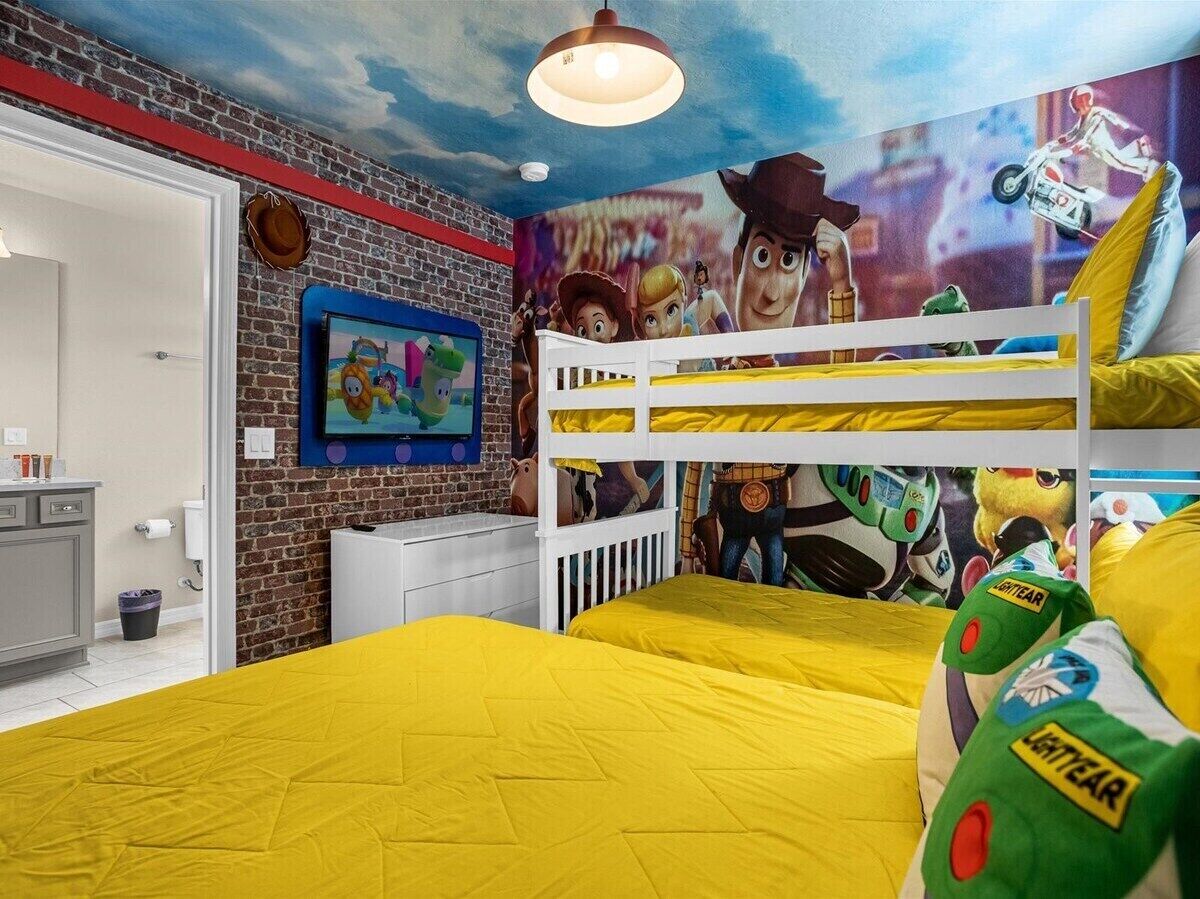 A child's bedroom with a bunk bed, a mural of animated characters, and a brick wall design.