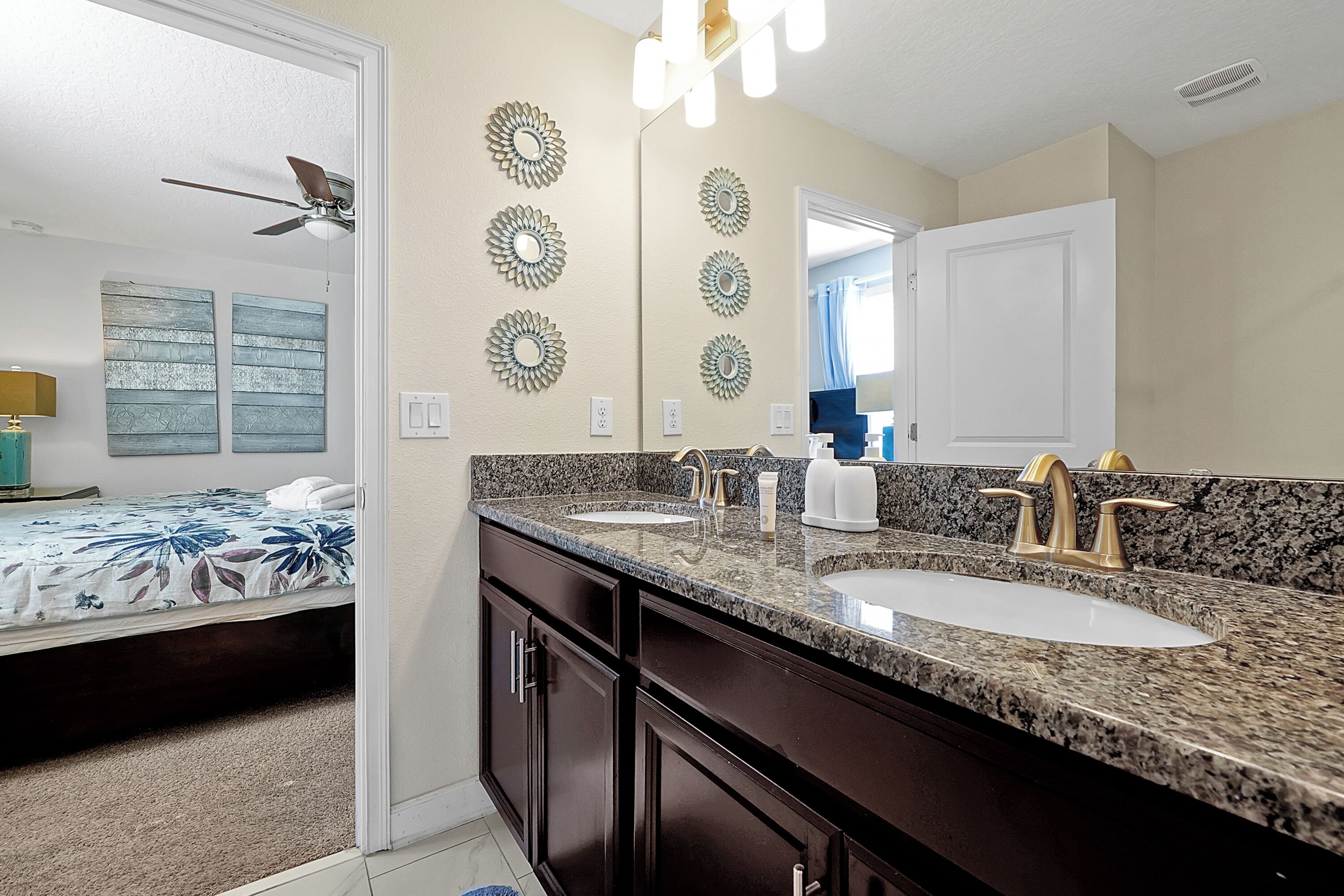A bathroom with two sinks, a ceiling fan, and decorative wall mirrors.