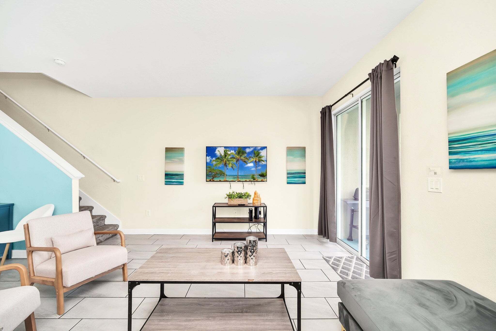 A living room with a sofa, a coffee table, a TV, a bookshelf, and a staircase.